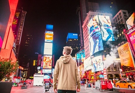 Digital billboard advertising by Uprides Ads, seen by a man in an urban setting.