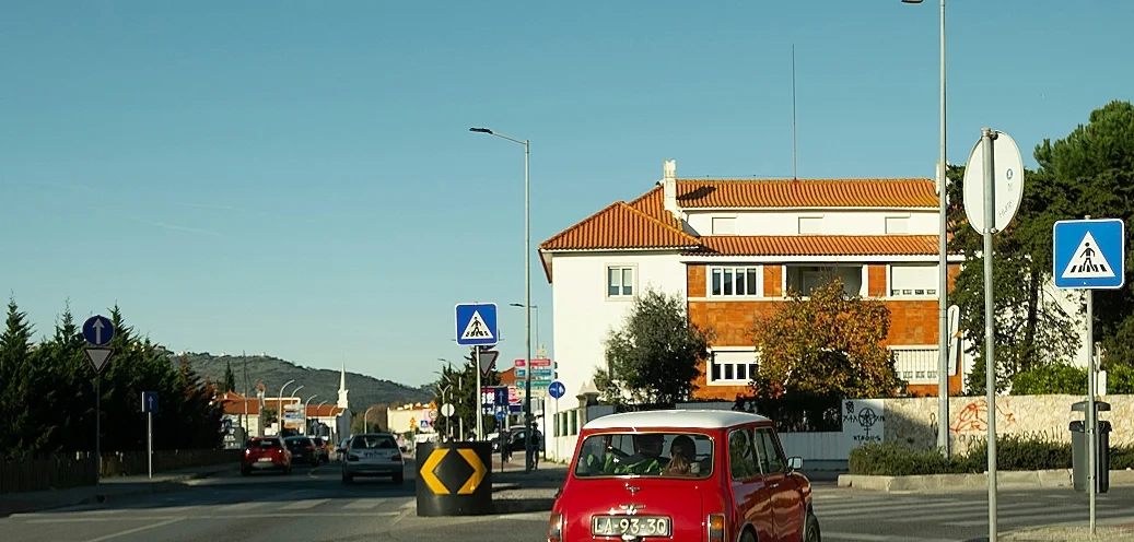 White house beside a street with cars with a red car in front.