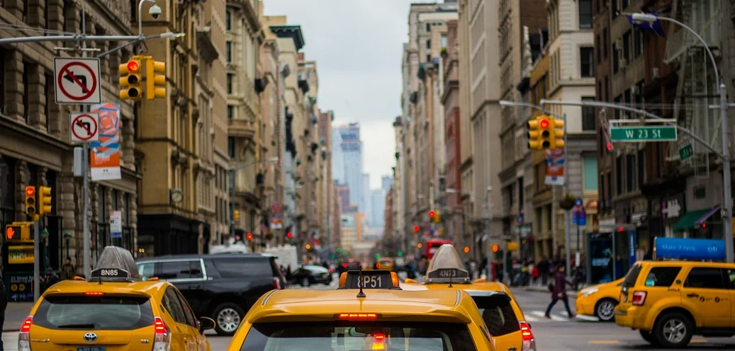 Group of yellow taxis on a busy city highway.